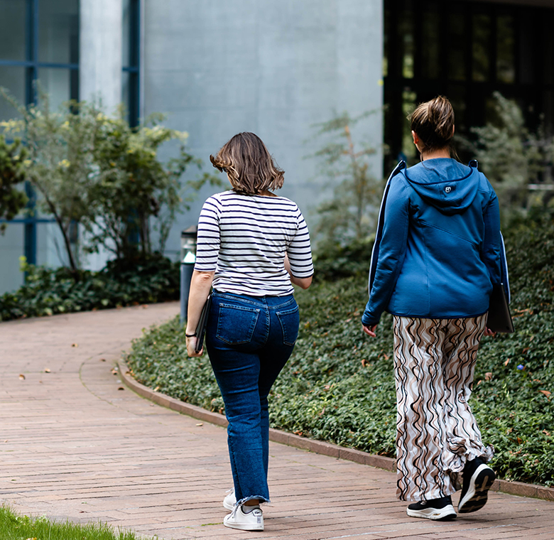 Two Monte Rosa team members walk toward the main building on the grounds of the Basel location.