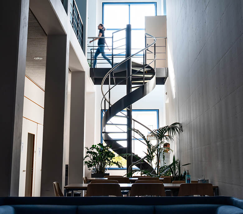 Monte Rosa staff walk by the spiral staircase in the Basel location.